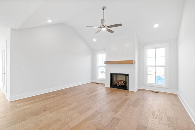 unfurnished living room with vaulted ceiling, a large fireplace, ceiling fan, and light wood-type flooring