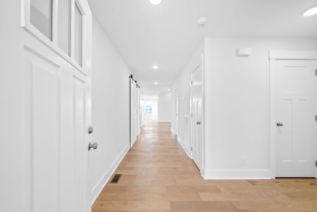 corridor with light hardwood / wood-style flooring and a barn door