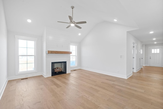 unfurnished living room featuring ceiling fan, a large fireplace, lofted ceiling, and light wood-type flooring