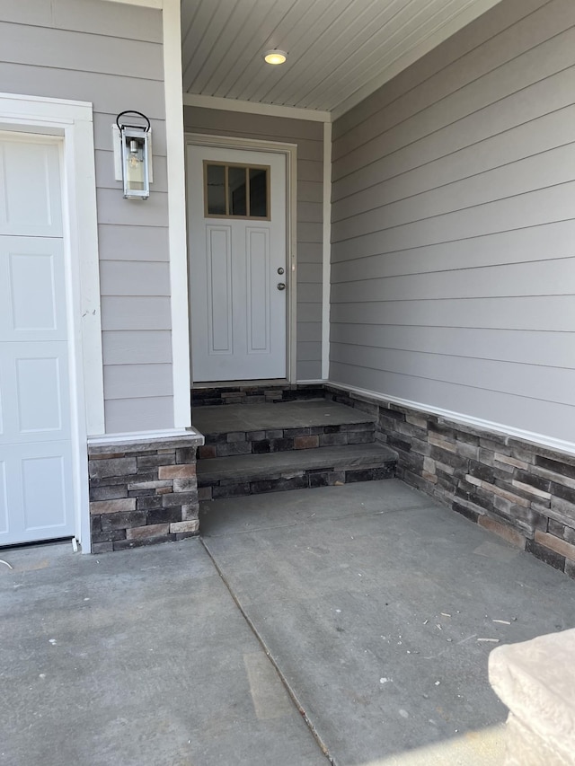 view of exterior entry with a garage and stone siding