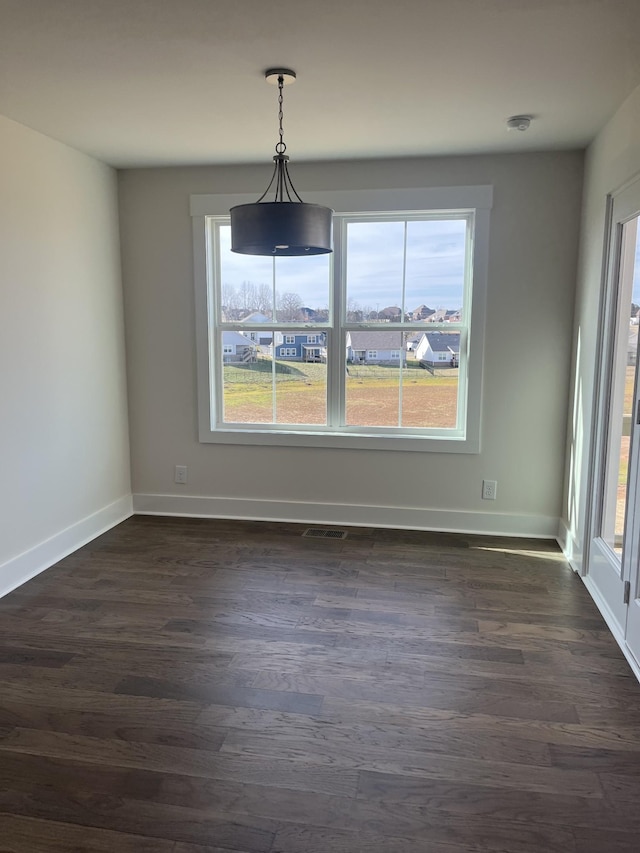 unfurnished dining area with dark wood-style floors, visible vents, and a wealth of natural light