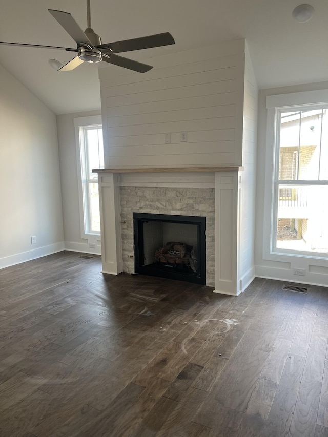 unfurnished living room with visible vents, dark wood-type flooring, baseboards, lofted ceiling, and a fireplace