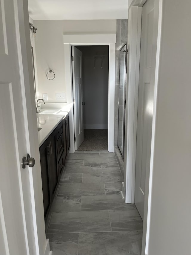 full bath featuring vanity, a shower stall, a walk in closet, and marble finish floor