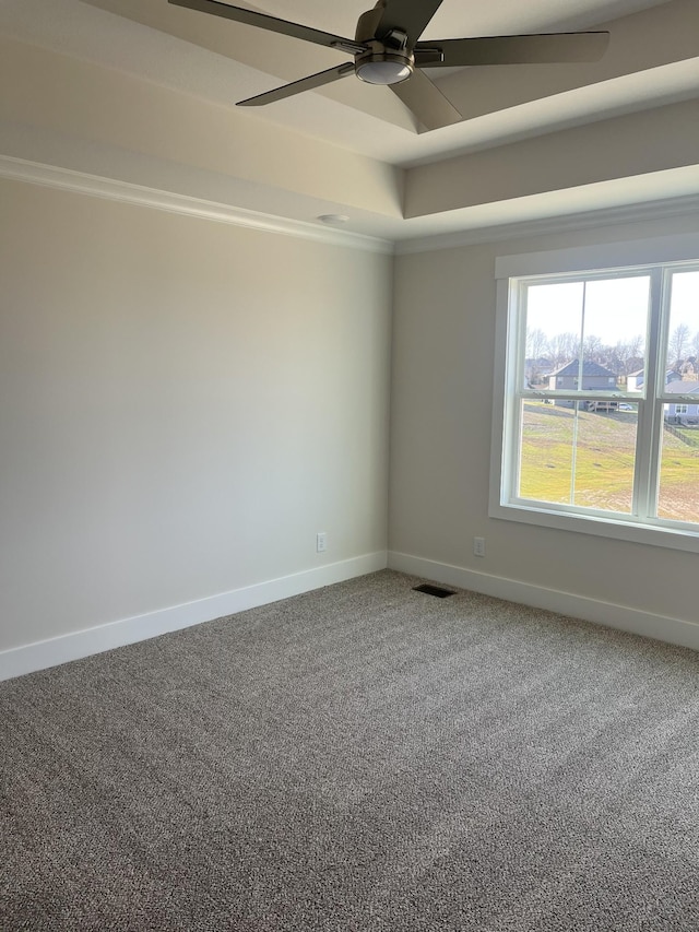 carpeted spare room featuring a tray ceiling, visible vents, baseboards, and ceiling fan