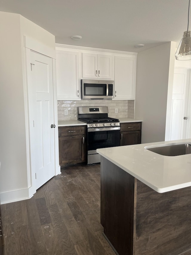 kitchen featuring dark wood finished floors, backsplash, appliances with stainless steel finishes, and light countertops