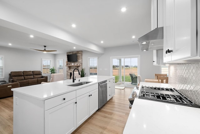 kitchen featuring a center island with sink, sink, appliances with stainless steel finishes, white cabinetry, and extractor fan