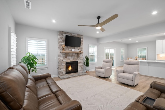 living room with ceiling fan, a fireplace, a healthy amount of sunlight, and light hardwood / wood-style floors