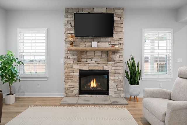 living room featuring light wood-type flooring and a stone fireplace