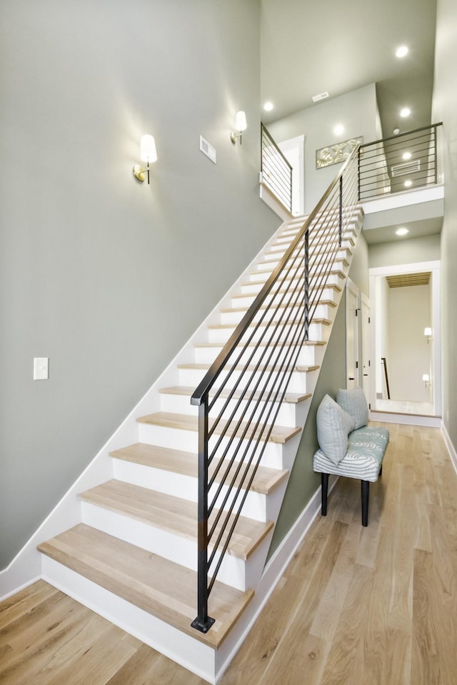 stairway with a high ceiling and wood-type flooring