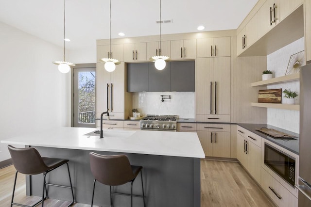 kitchen featuring an island with sink, cream cabinets, sink, and pendant lighting