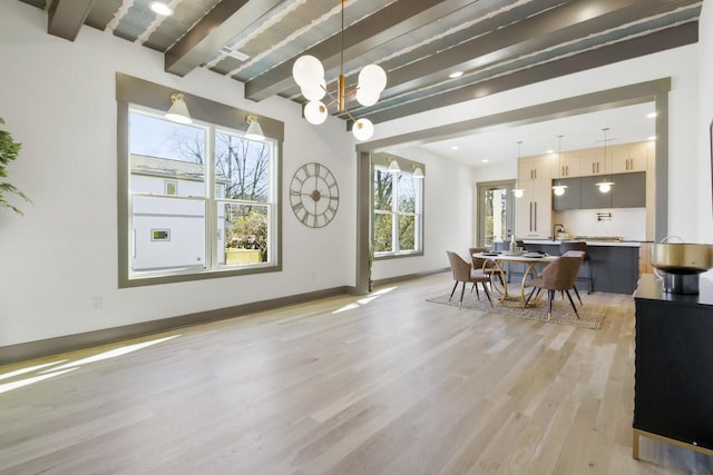 dining area with a notable chandelier, beam ceiling, and light wood-type flooring