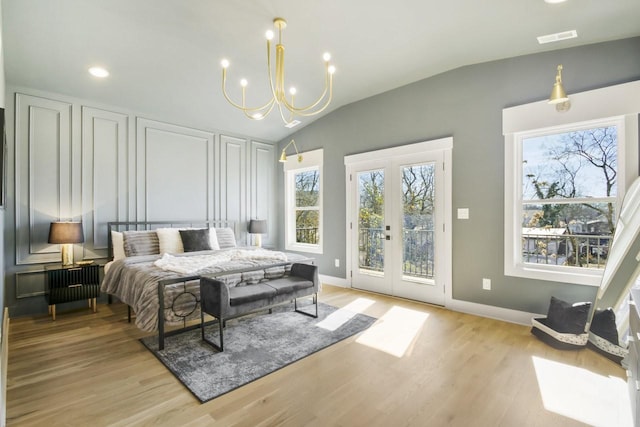 bedroom featuring lofted ceiling, light wood-type flooring, access to exterior, an inviting chandelier, and french doors