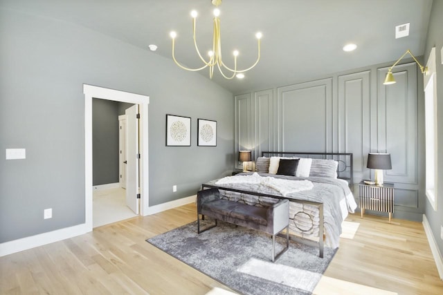 bedroom with an inviting chandelier, lofted ceiling, and light hardwood / wood-style floors