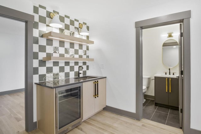 bar featuring sink, wine cooler, and light wood-type flooring