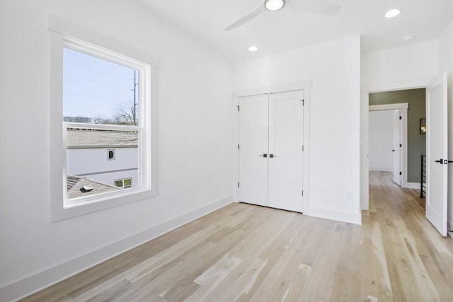 unfurnished bedroom featuring ceiling fan, a closet, and light wood-type flooring