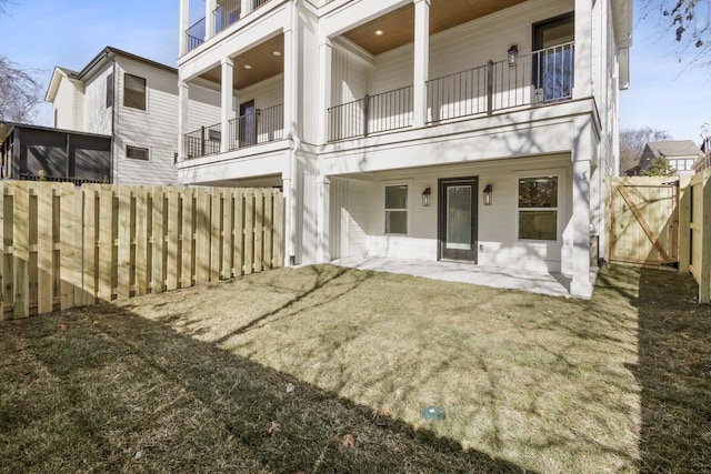 rear view of property featuring a balcony, a lawn, and a patio area