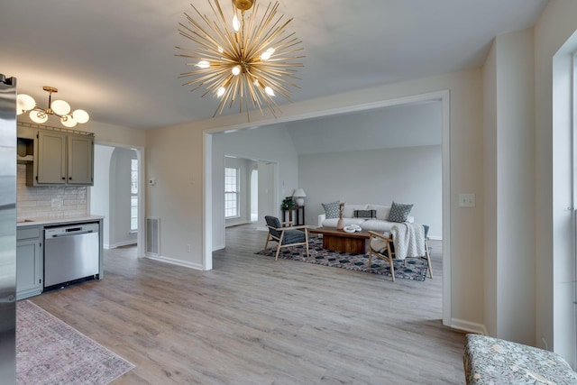 kitchen with dishwasher, light wood-type flooring, backsplash, and a chandelier