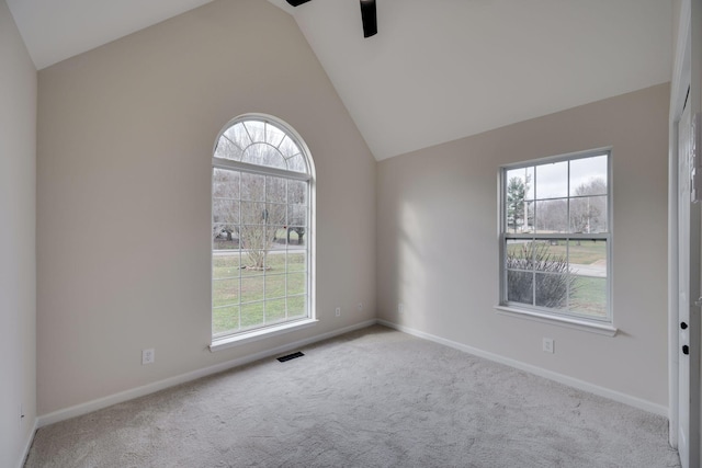 carpeted empty room with a wealth of natural light, ceiling fan, and vaulted ceiling