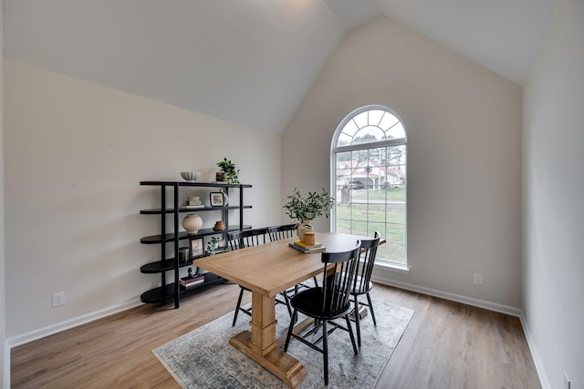 dining space featuring light hardwood / wood-style floors, a wealth of natural light, and vaulted ceiling