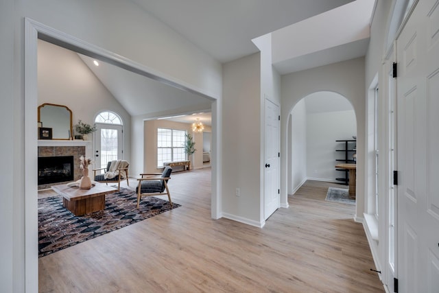 entryway featuring a fireplace, light hardwood / wood-style floors, and high vaulted ceiling