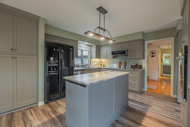 kitchen with appliances with stainless steel finishes, light wood-type flooring, sink, decorative light fixtures, and a center island