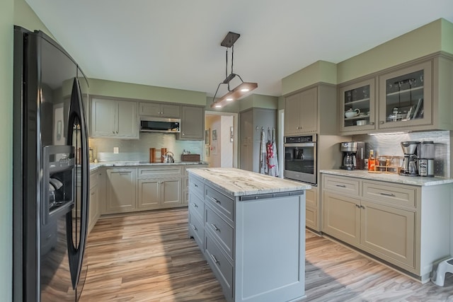 kitchen featuring a center island, hanging light fixtures, light hardwood / wood-style flooring, decorative backsplash, and stainless steel appliances