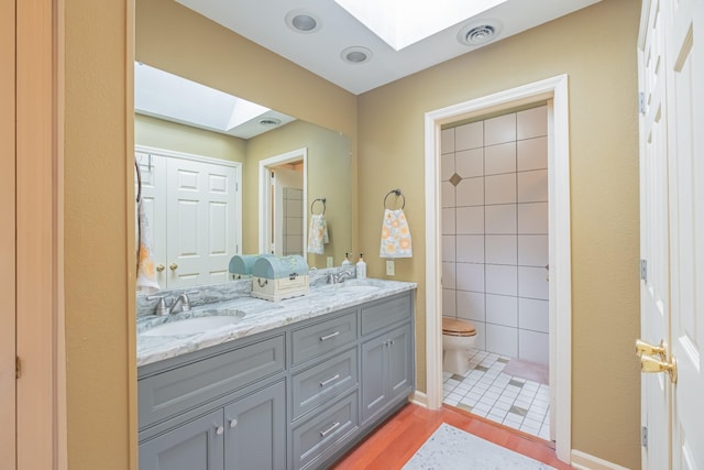 bathroom with a skylight, tile patterned flooring, vanity, and toilet