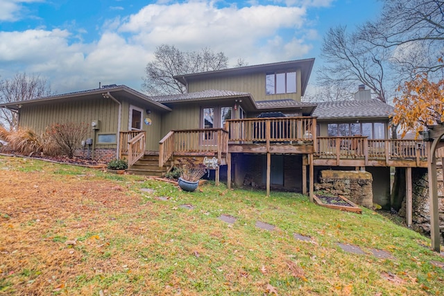 rear view of house with a wooden deck and a yard