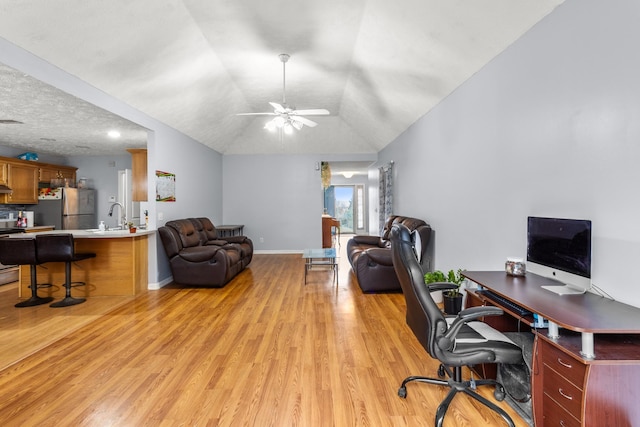 office featuring lofted ceiling, sink, ceiling fan, a textured ceiling, and light hardwood / wood-style floors