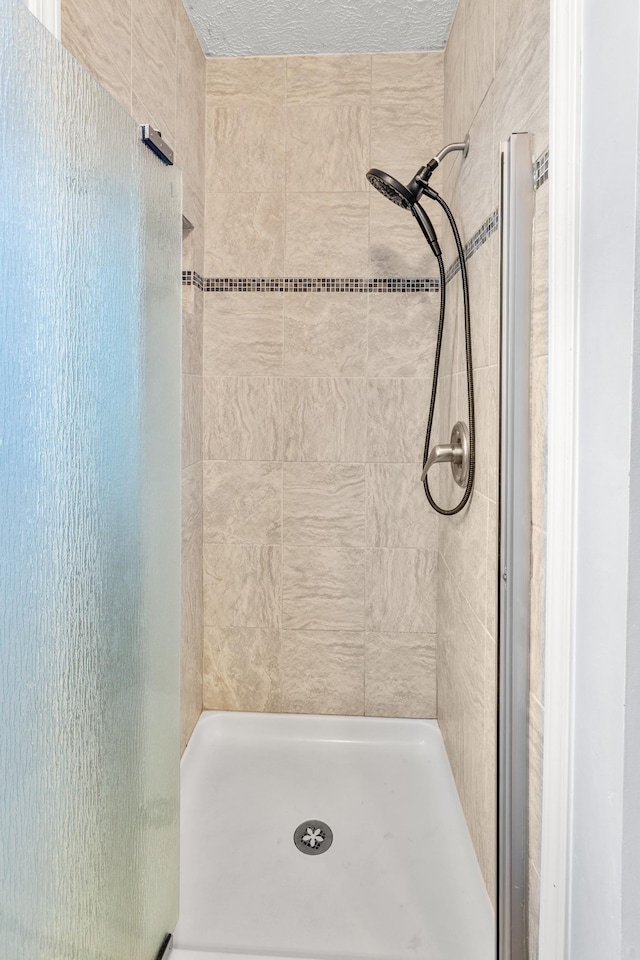 bathroom featuring a tile shower and a textured ceiling