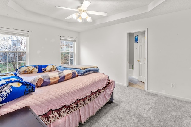 carpeted bedroom with ceiling fan, a textured ceiling, and a tray ceiling