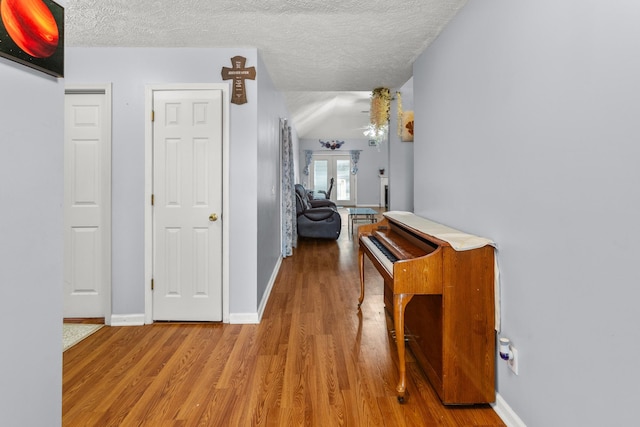 hall with wood-type flooring and a textured ceiling