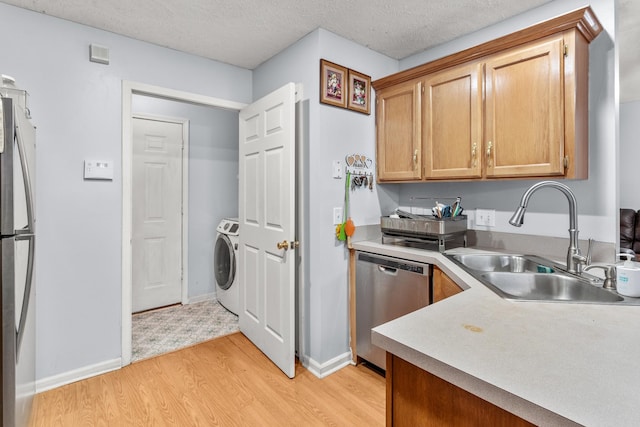 kitchen featuring sink, washer / clothes dryer, light hardwood / wood-style floors, a textured ceiling, and appliances with stainless steel finishes