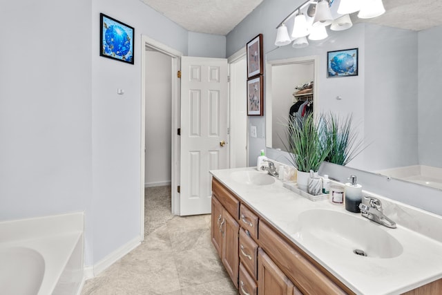 bathroom featuring vanity, an inviting chandelier, tile patterned floors, a textured ceiling, and a tub