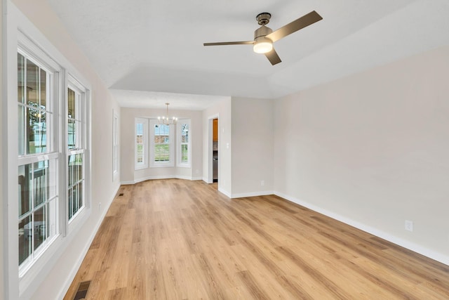 spare room with ceiling fan with notable chandelier, light hardwood / wood-style floors, and vaulted ceiling