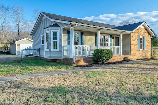 view of front of property featuring an outbuilding, a front lawn, covered porch, and a garage