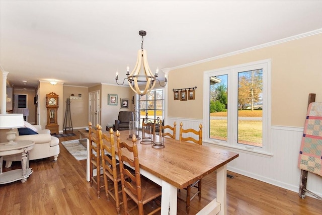 dining area with crown molding, wood-type flooring, and a notable chandelier