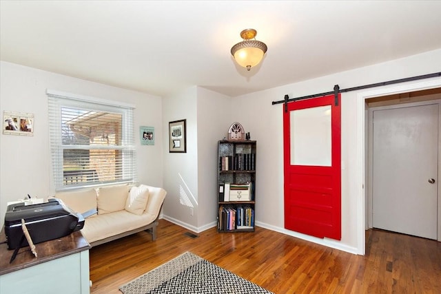 living area featuring a barn door and wood-type flooring