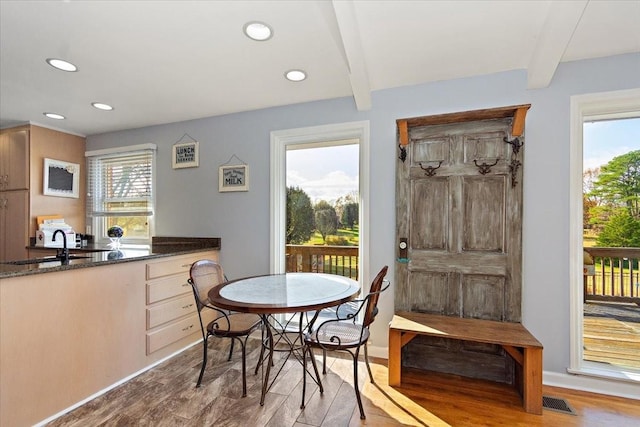 dining space featuring beam ceiling, light wood-type flooring, and a wealth of natural light