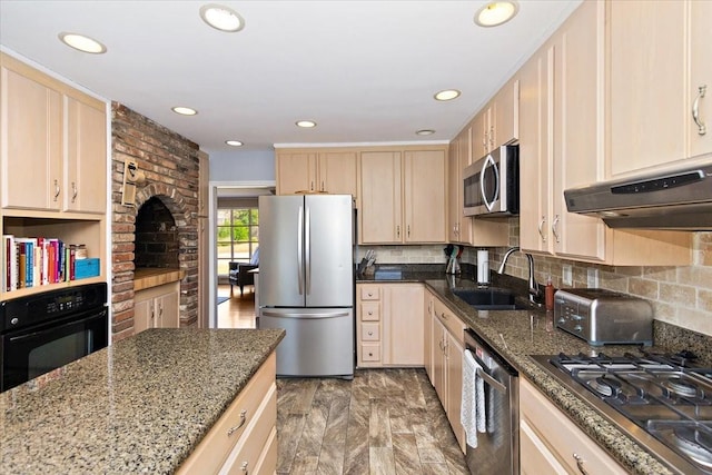 kitchen featuring appliances with stainless steel finishes, light brown cabinets, dark stone counters, and sink