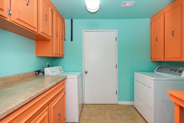 washroom featuring cabinets, light tile patterned floors, and washing machine and clothes dryer