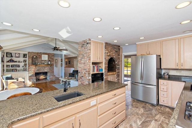 kitchen featuring light brown cabinets, sink, appliances with stainless steel finishes, and a brick fireplace