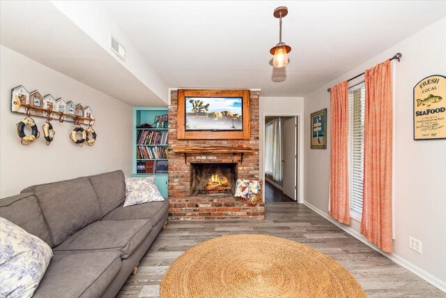 living room featuring hardwood / wood-style flooring and a brick fireplace