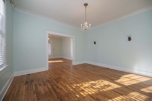 empty room with ornamental molding, hardwood / wood-style floors, and a chandelier