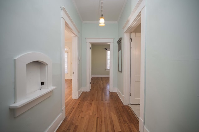 corridor with ornamental molding and light hardwood / wood-style floors