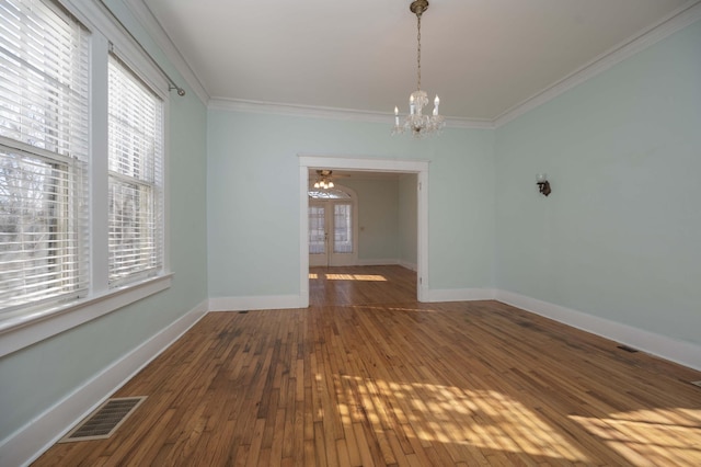 unfurnished dining area with an inviting chandelier, hardwood / wood-style floors, crown molding, and french doors