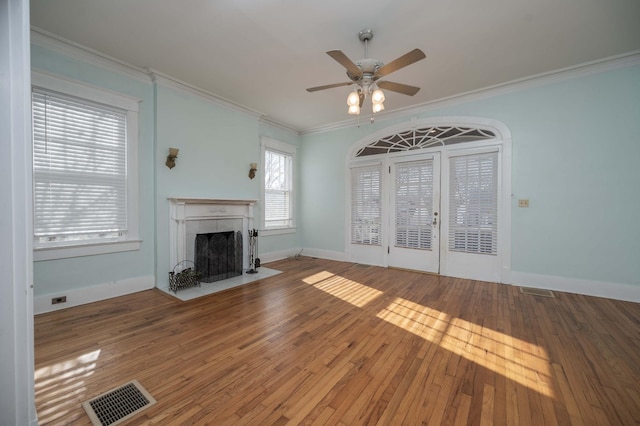 unfurnished living room featuring crown molding, ceiling fan, wood-type flooring, and a tiled fireplace