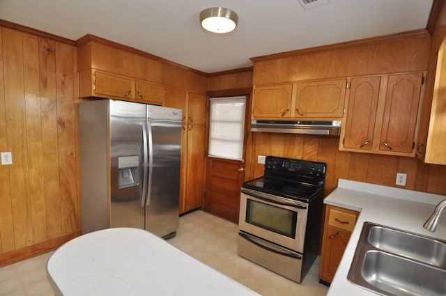 kitchen with sink, wooden walls, stainless steel appliances, and ornamental molding