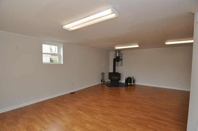 basement featuring a wood stove and light hardwood / wood-style flooring