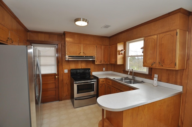 kitchen with appliances with stainless steel finishes, kitchen peninsula, sink, and wood walls